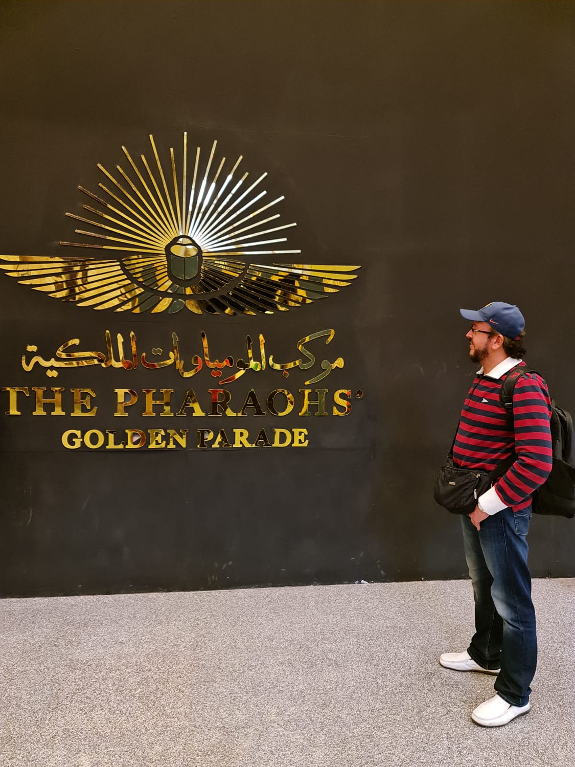 Traveller beside the Pharaohs' Golden Parade emblem at the National Museum of Egyptian Civilization