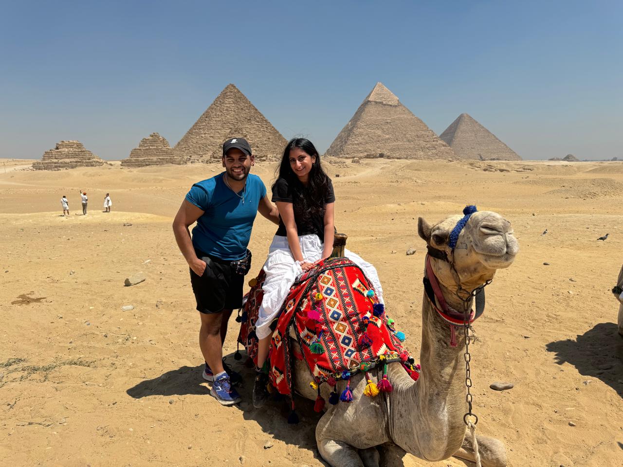 Couple with a decorated camel in front of the Giza pyramids